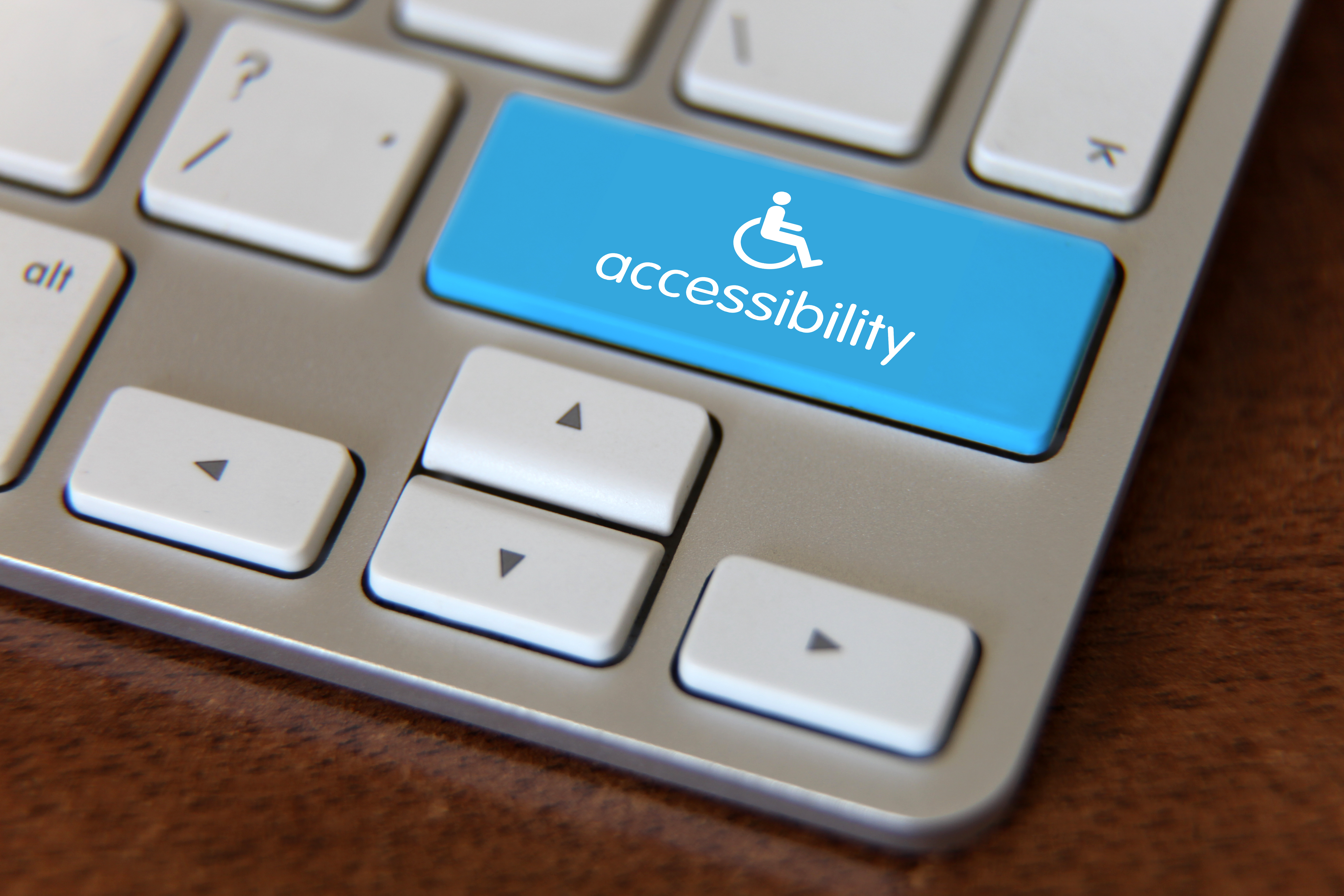 Image of a keyboard and a blue button above the arrow keys of the handicap symbol with "accessibility" written under it.